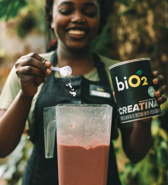 Mulher colocando creatina em um Liquidificador